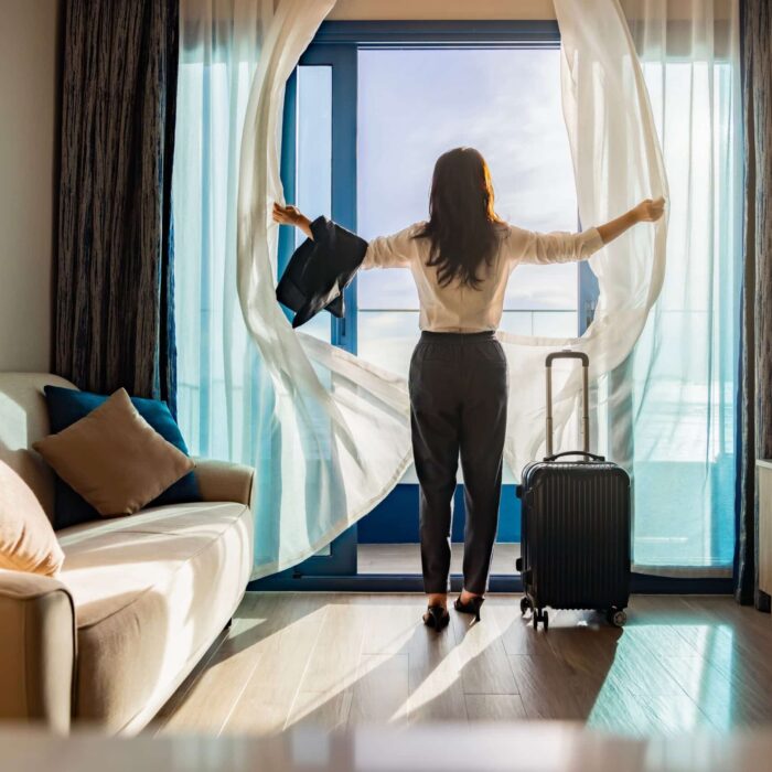 Attractive,Businesswoman,With,Suitcase,Opening,Curtains,,Looking,At,The,View Rénovation énergétique en copropriété : ce qui change en 2025